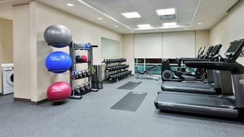 A gym with treadmills, dumbbells, and exercise balls.
