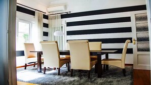 A dining area with a black and white striped wall, a table with chairs, and a rug. - Acropolis detached house (Athens)
