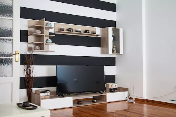 A modern living room with a flat-screen TV, wooden shelves, and a minimalist design. - Acropolis detached house (Athens)