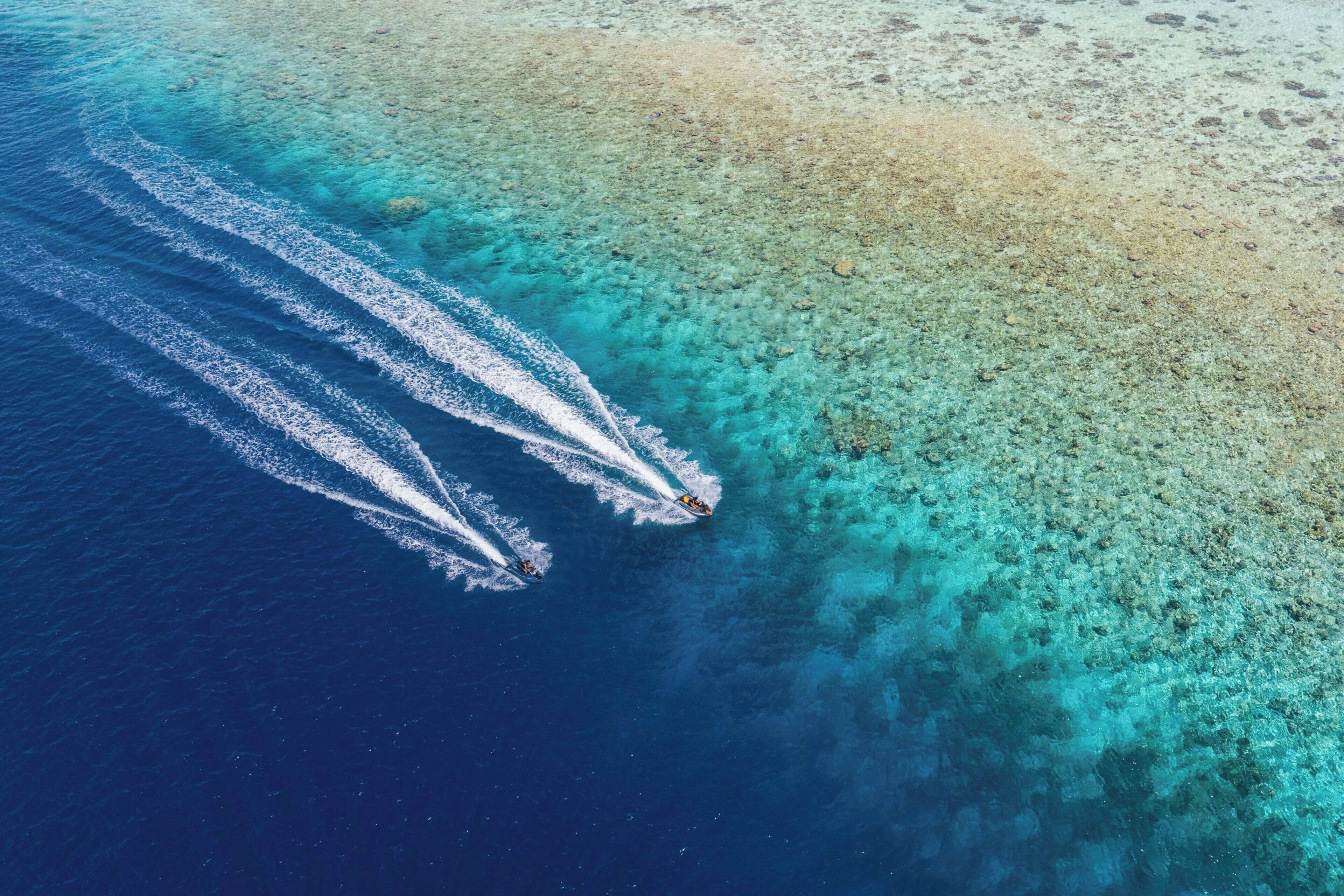 Vista aérea de una playa con aguas turquesas cristalinas y una orilla arenosa.