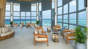 A spacious indoor area with large windows, wooden furniture, and a view of the ocean. - The Halcyon Private Isles Maldives, Autograph Collection (Meradhoo)