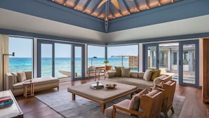 A spacious living room with a large window offering a view of the ocean, a ceiling fan, and a seating area with a sofa and chairs. - The Halcyon Private Isles Maldives, Autograph Collection (Meradhoo)