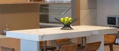 A modern kitchen with a central island, bar stools, pendant lighting, and open shelving with decorative items.