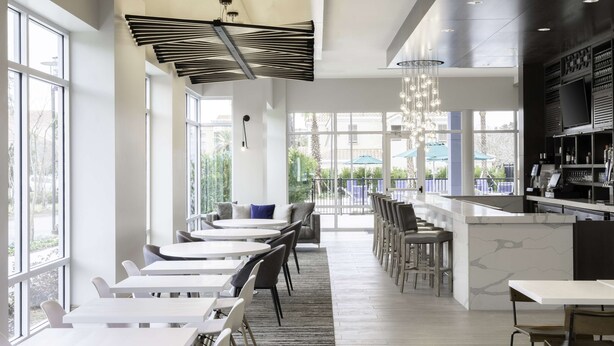 Zona pranzo moderna con soffitti alti, ampie finestre e un'area bar centrale.