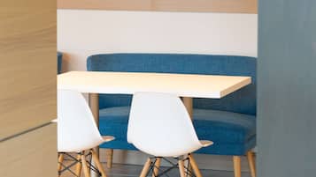 A modern seating area with a wooden slatted ceiling, a blue sofa, and a white table with two chairs.