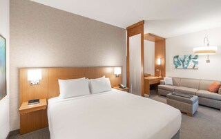 Habitación de hotel con una cama grande, un escritorio, un sofá y un baño visible a través de una puerta abierta.