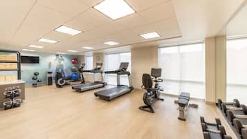 Ein Fitnessstudio mit Laufbändern, Crosstrainern und Kurzhanteln.