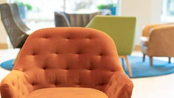 Un sillón con textura en una habitación moderna, con otras sillas contemporáneas y una alfombra azul.