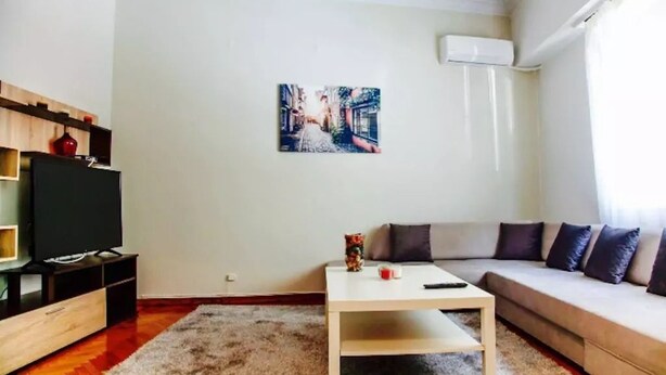 A modern living room with a flat-screen TV, a white coffee table, a sofa, and a painting on the wall. - Acropolis modern house (Athens)