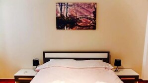 A neatly made bed with towels, a painting of a bridge, and bedside lamps. - Acropolis modern house (Athens)