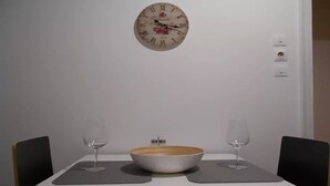 A dining table with two wine glasses and a bowl, a wall clock, and a power outlet. - Acropolis modern house (Athens)