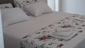 Una cama bien hecha con ropa de cama floral, un cabecero y una mesita de noche con lámpara.
