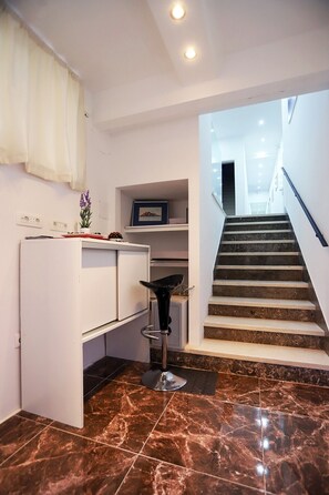 Una cocina moderna con un refrigerador blanco, un taburete negro y un piso de mármol.