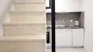 Una escalera conduce a una cocina con armarios blancos y salpicadero de azulejos.
