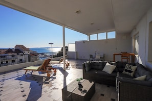 A spacious balcony with a view of the sea, a wicker sofa, and a small table with a plant. - Villa Zvonko (Split)