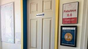 A hotel room door with a sign indicating restrooms. There are two framed awards on the wall: one for 'Fabulous 8.8' from Hotels.com and another for '8.4' from Booking.com. - Williams AZ Hostel (Williams)