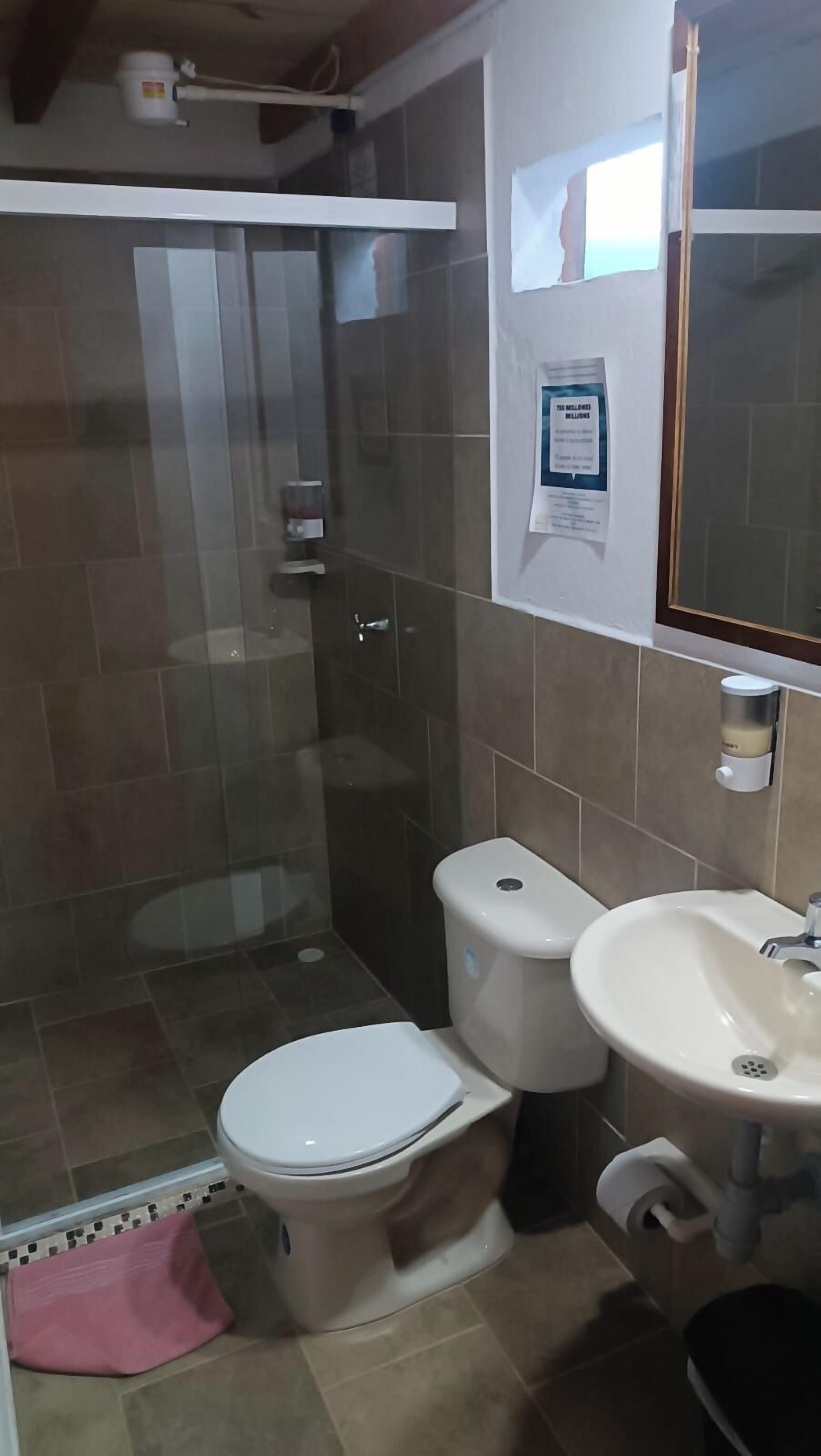 A bathroom with a toilet, sink, and glass shower enclosure.