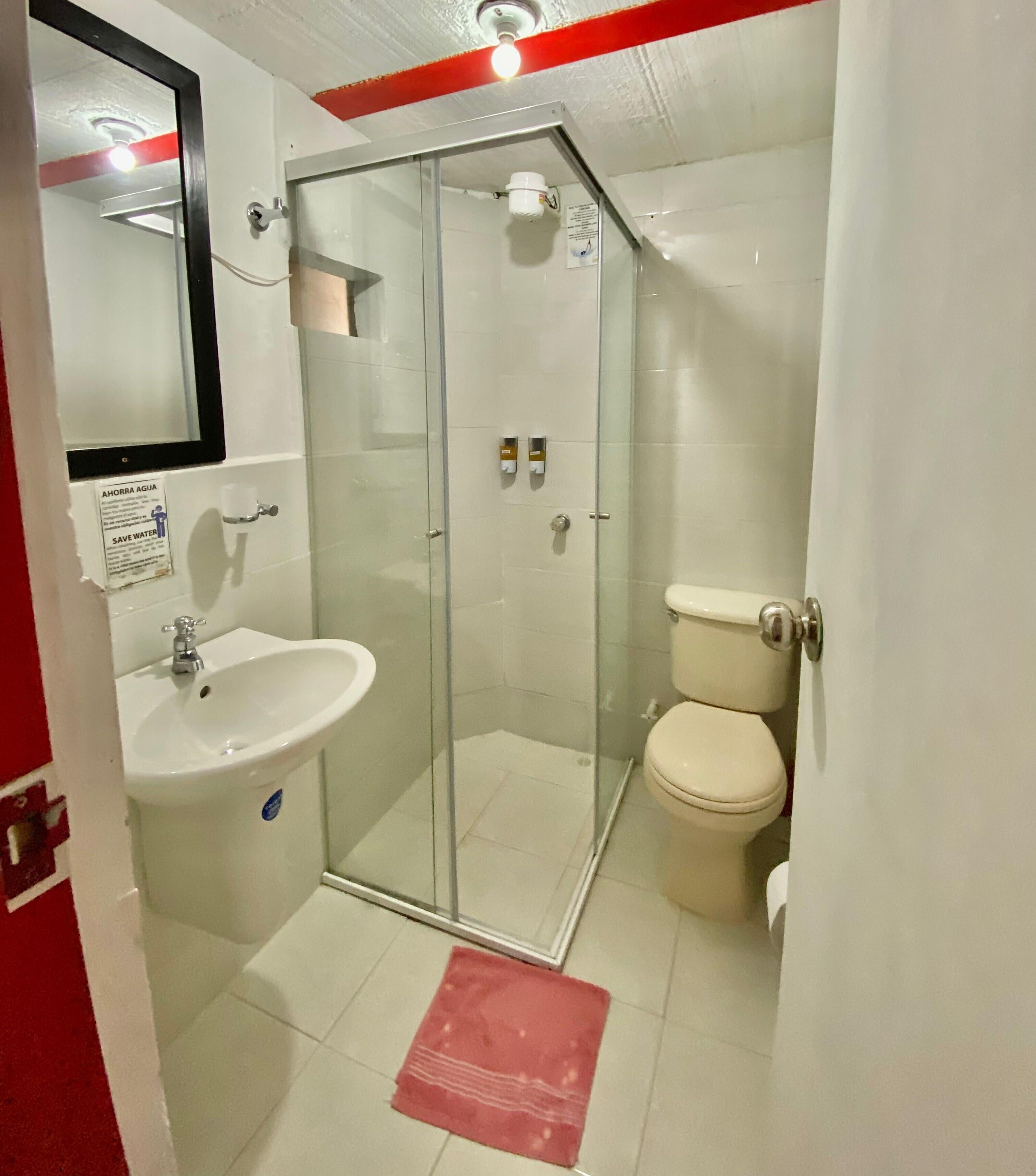 A bathroom with a glass-enclosed shower, a sink, and a toilet.