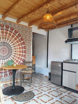 A kitchen with a patterned backsplash, a hanging light fixture, and a refrigerator. - Hotel Marrokos (Guarne)