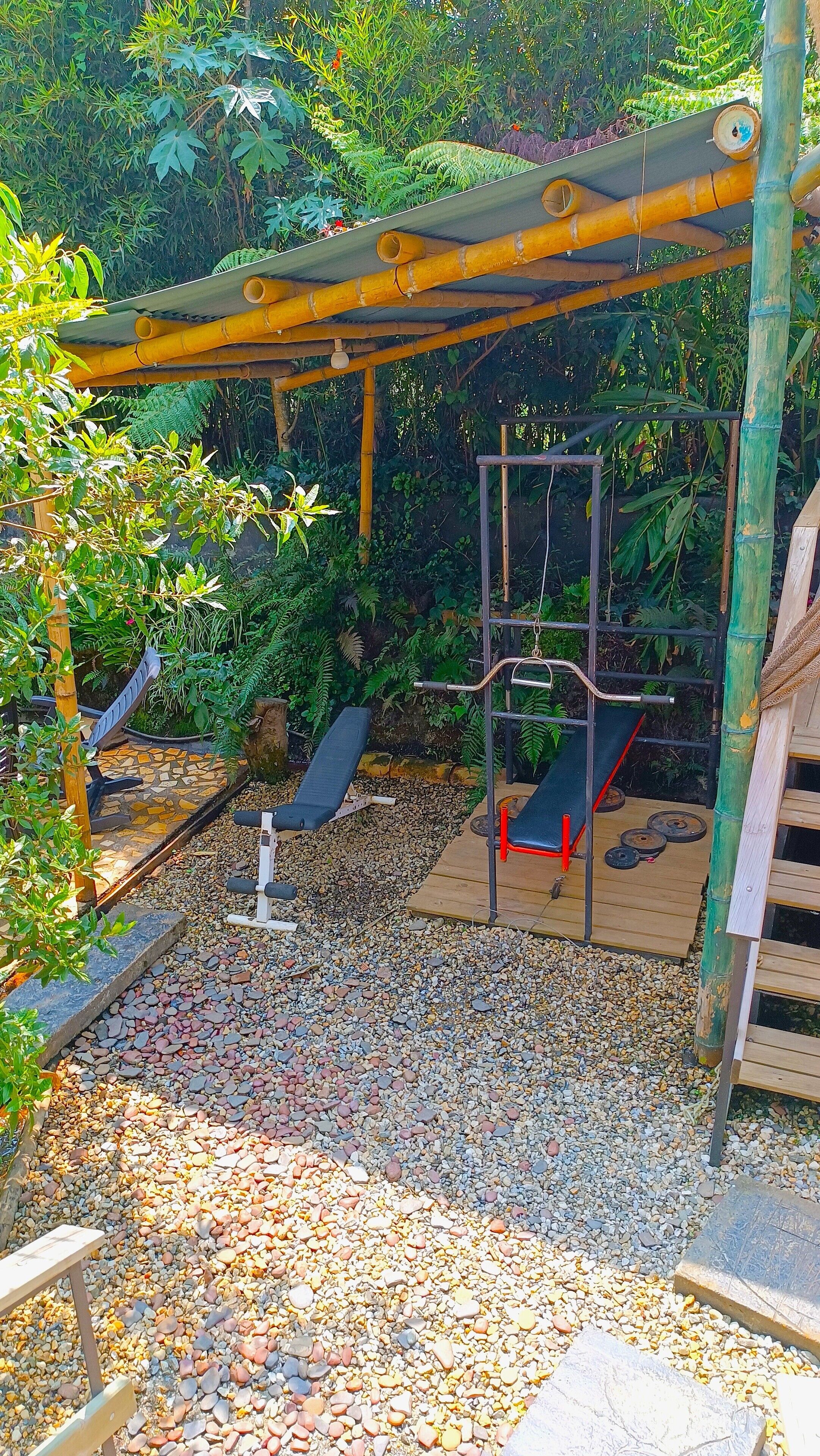 Un espacio al aire libre cubierto con una estructura de escalada, asientos y un pequeño jardín.