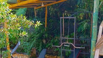 Un espacio al aire libre cubierto con una estructura de escalada, asientos y un pequeño jardín.