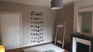 A bedroom with a bed, a hanging light fixture, a mirror, and a wall-mounted coat rack.