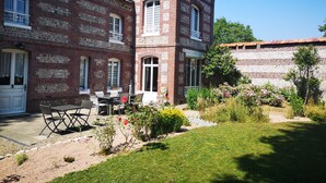 A two-story brick house with a patio area featuring a table and chairs.