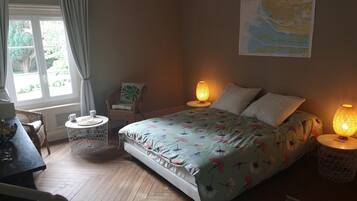 Een slaapkamer met een bed, twee bedlampen, een stoel, een kleine tafel en een kaart aan de muur.