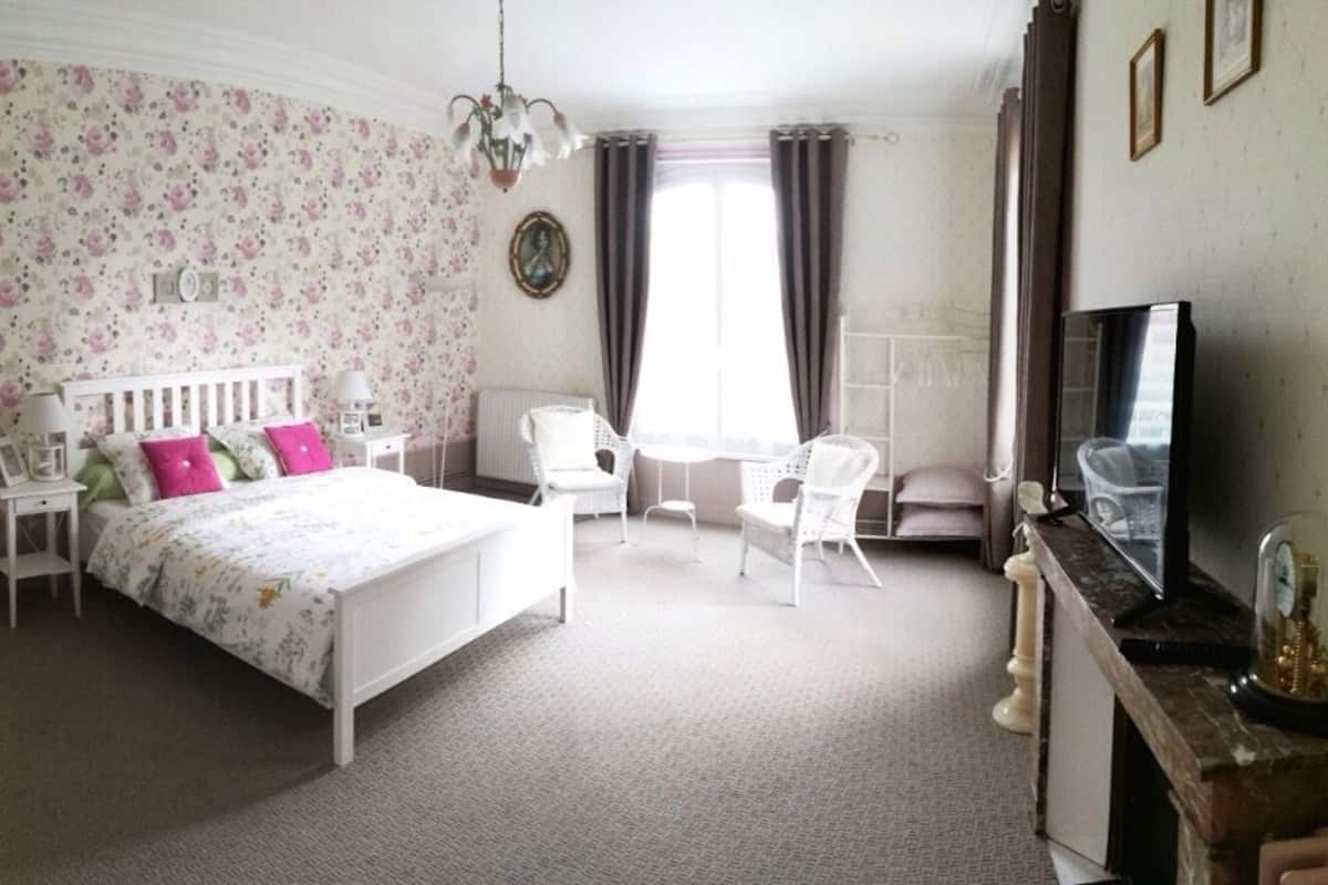 A bedroom with a bed, bedside tables, a chair, a TV, and a dresser.