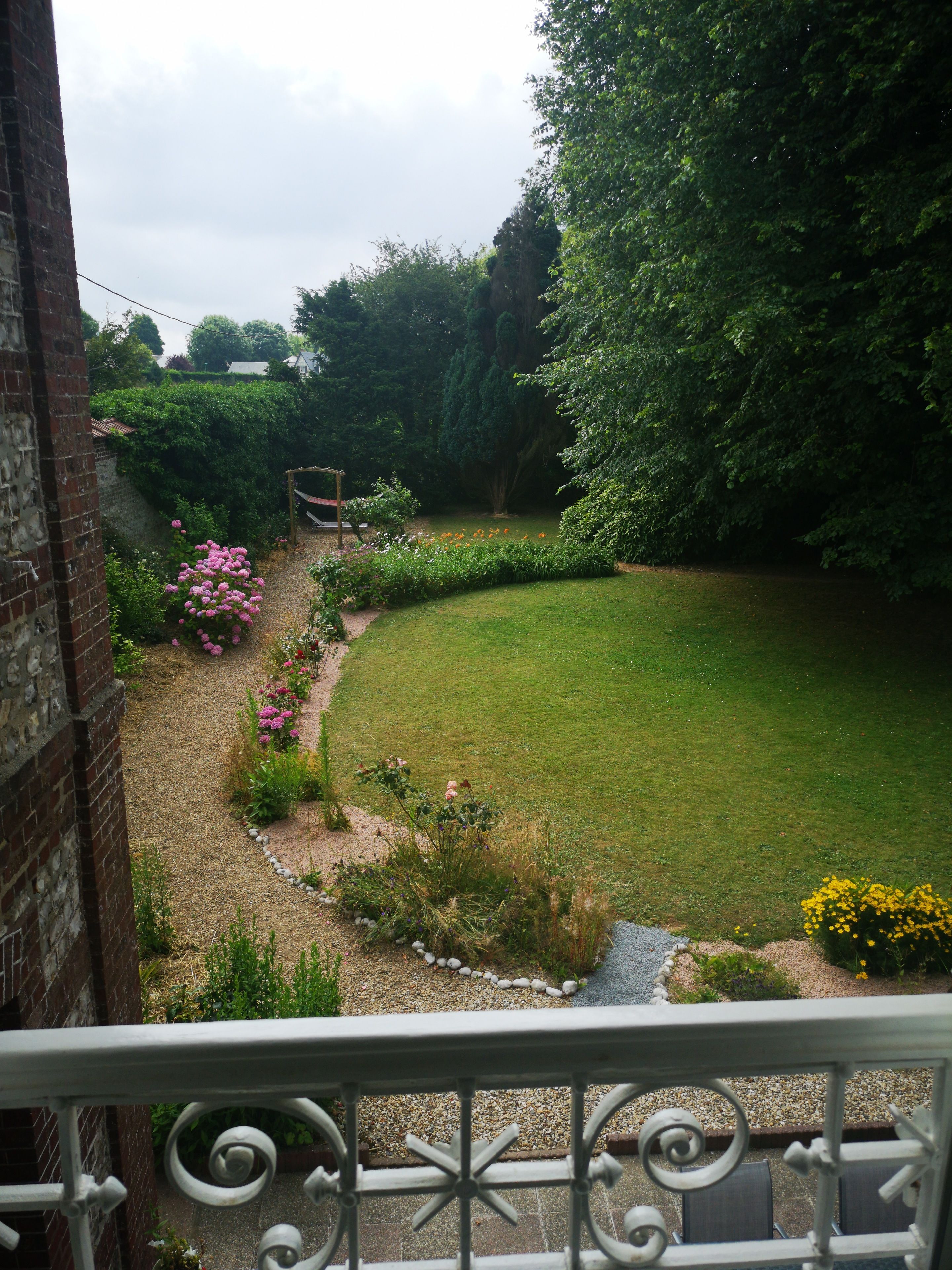 A garden with a grassy lawn, a brick wall, and a metal railing.
