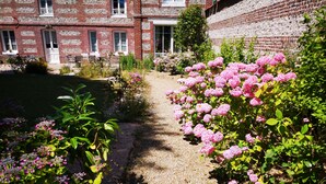 A garden path leading to a brick building with a white door and windows.