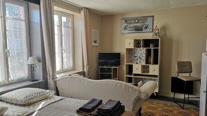 A hotel room with a bed, a TV, a desk, a chair, and a bookshelf.