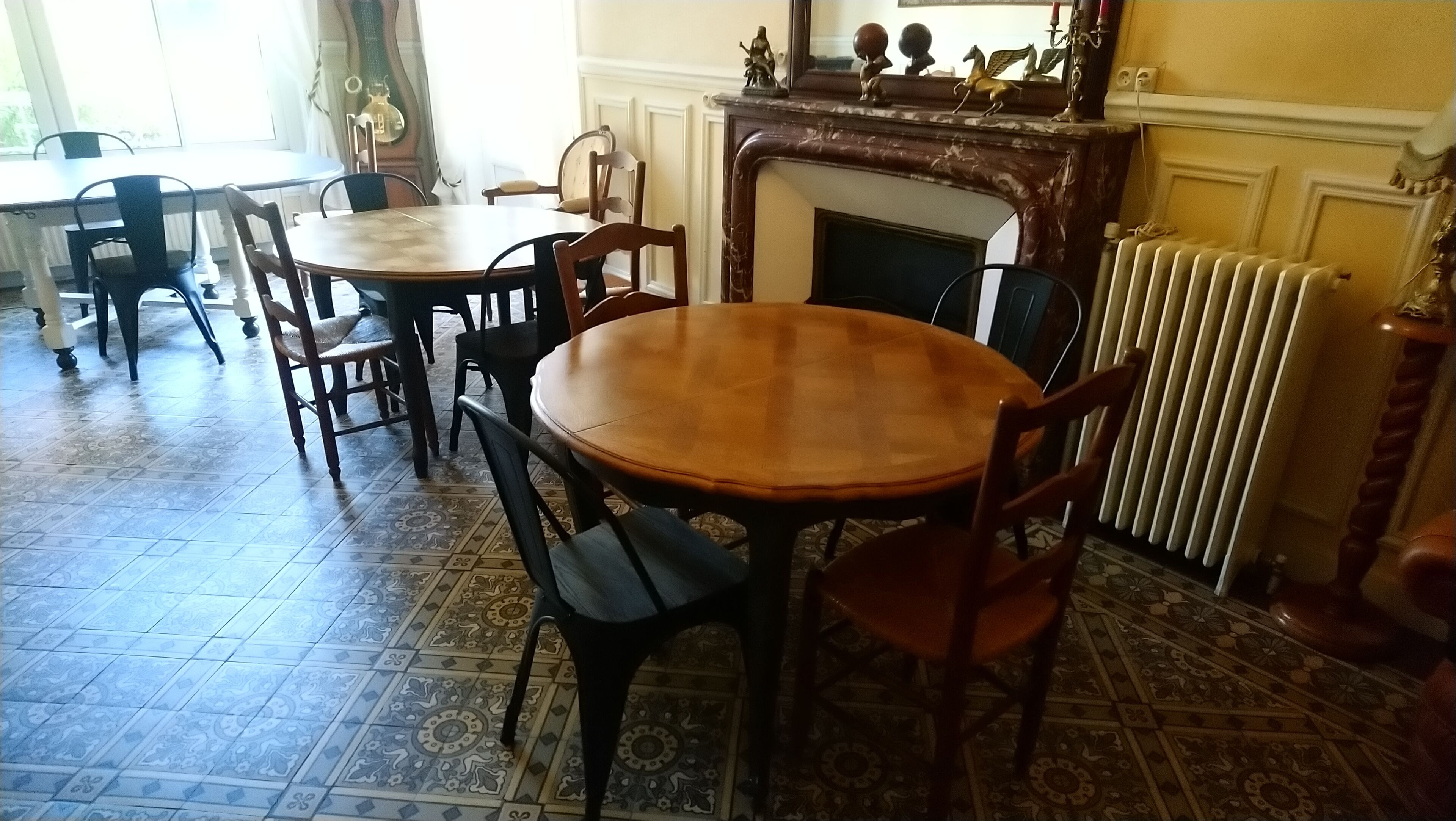 Comedor con una mesa redonda de madera, sillas, chimenea y baldosas de suelo con diseños.