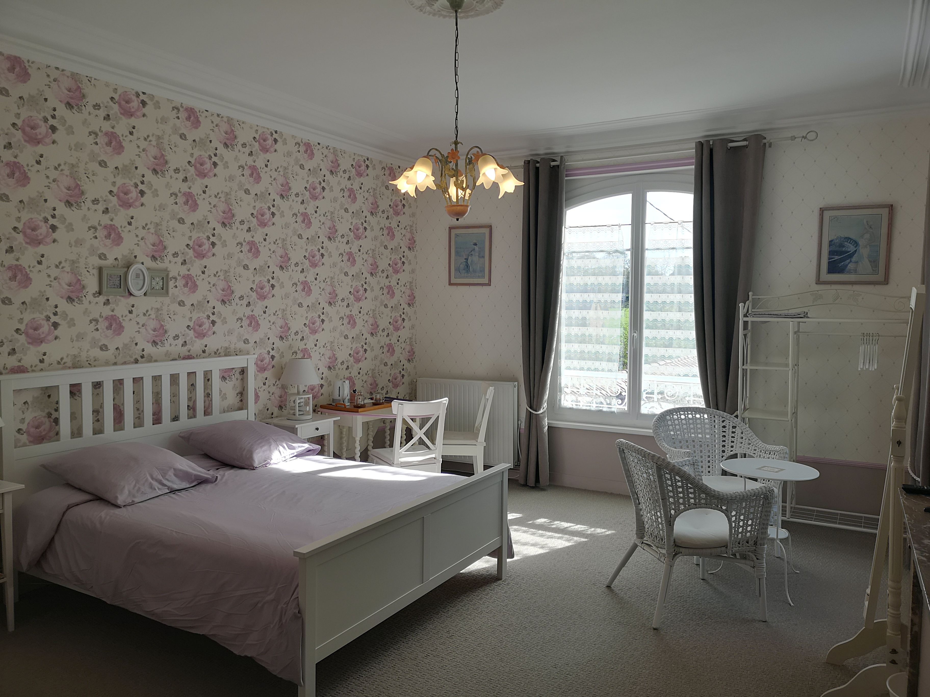 Een slaapkamer met een bed, een bureau, een stoel en een raam met gordijnen.