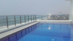 En swimmingpool med et glasværn og udsigt til havet.