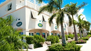Ein Hotel mit weißer Fassade, mehreren Balkonen und Palmen.