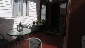 A patio with a round table and two chairs, a small potted plant, and a window with blinds. - Hostal Mirenart (Valparaiso)