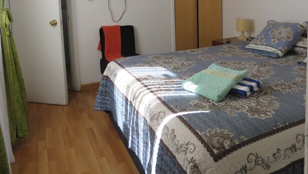 A bedroom with a bed, a television mounted on the wall, a wardrobe, and a door leading to another room. - Hostal Mirenart (Valparaiso)