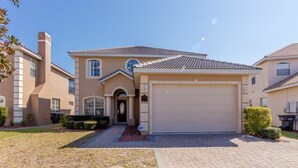 A two-story residential building with a beige facade, a tiled roof, and a garage. - Magical Villa with pool and spa in quiet community (Davenport)