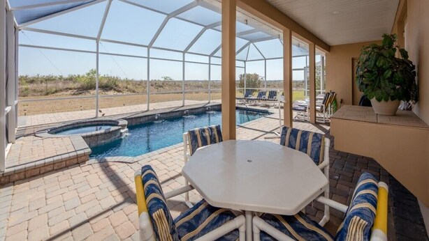 A covered outdoor area with a pool, seating, and a view of the landscape. - Magical Villa with pool and spa in quiet community (Davenport)