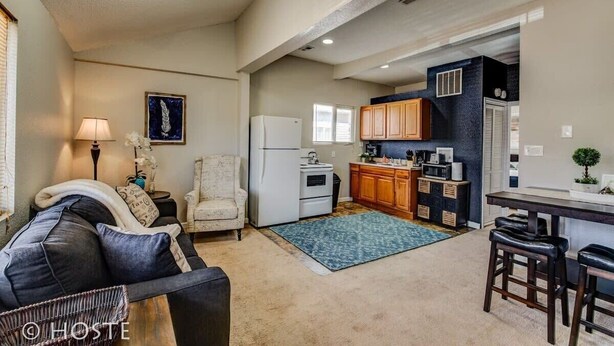 Un espacio habitable compacto con kitchenette, sofá, zona de comedor y pequeña cocina.