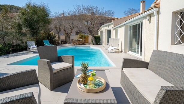 A backyard with a swimming pool, wicker furniture, and a tray with drinks.