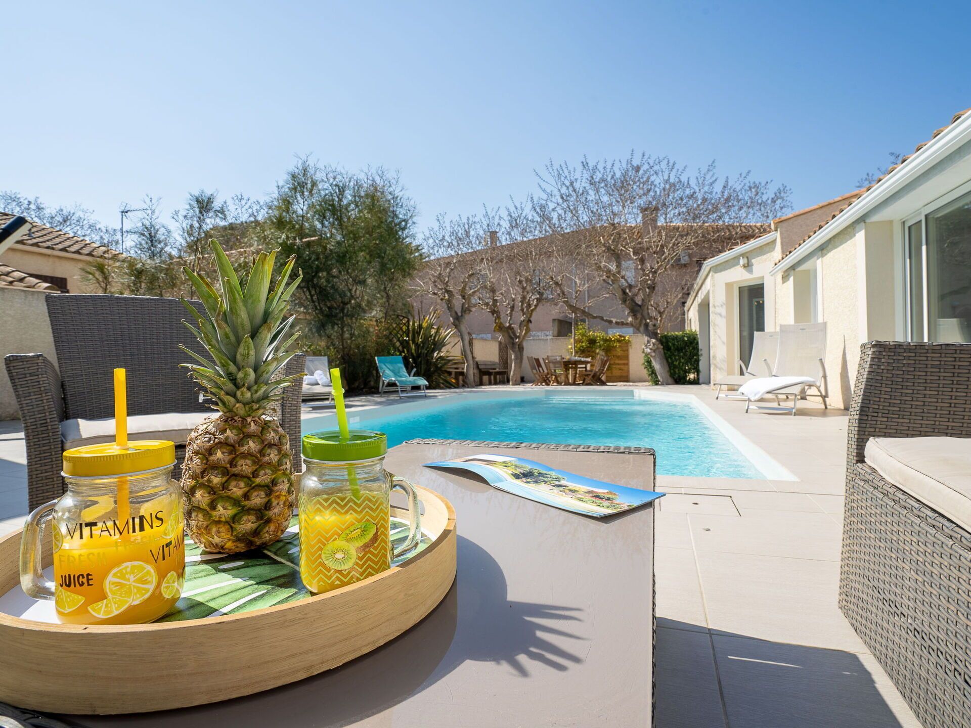 A poolside area with a table, lounge chairs, and a pool.
