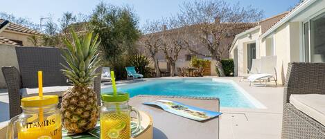 A poolside area with a table, lounge chairs, and a pool.