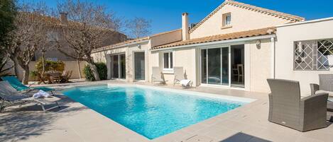 Une piscine avec des chaises longues et un espace patio.