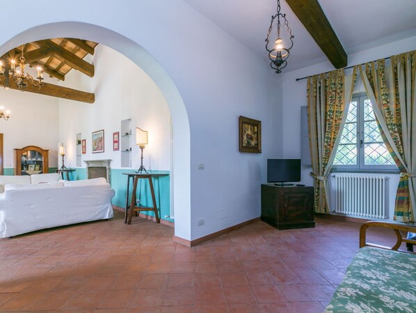 Una habitación con cama, televisión, chimenea y ventana con cortinas.