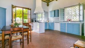 Una cocina con armarios azules, una mesa de comedor con sillas y una araña.