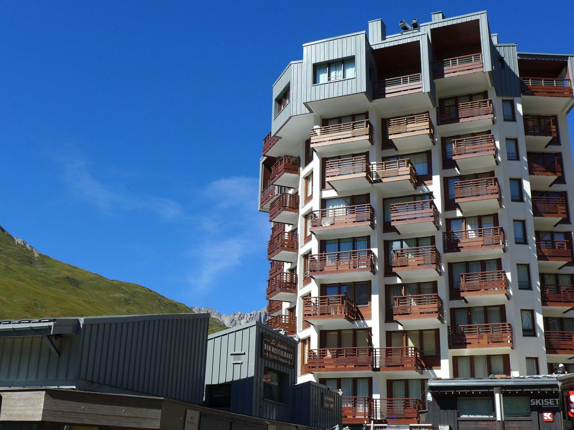 A multi-story hotel with balconies, a restaurant, and a ski rental sign.
