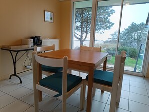 Een eetgedeelte met een houten tafel en stoelen, een koffiezetapparaat en een radiator.