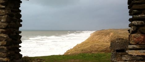 En stenbuet fører til et græsareal med udsigt over havet.